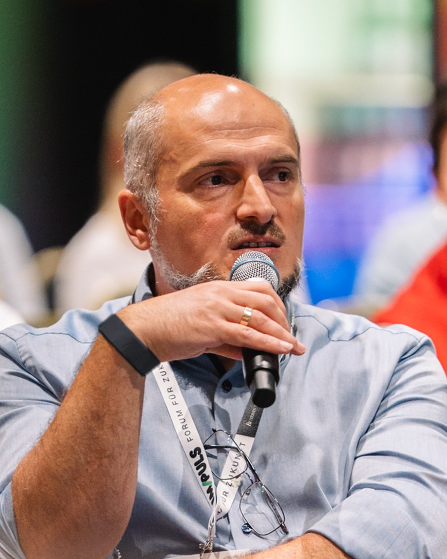 Engin Karahan spricht mit Mikrofon in einer Gesprächsrunde