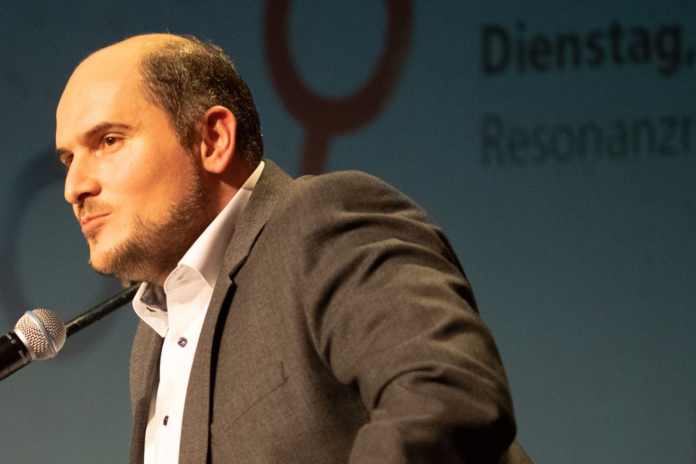 Engin Karahan spricht auf einem Podium in ein Mikrofon