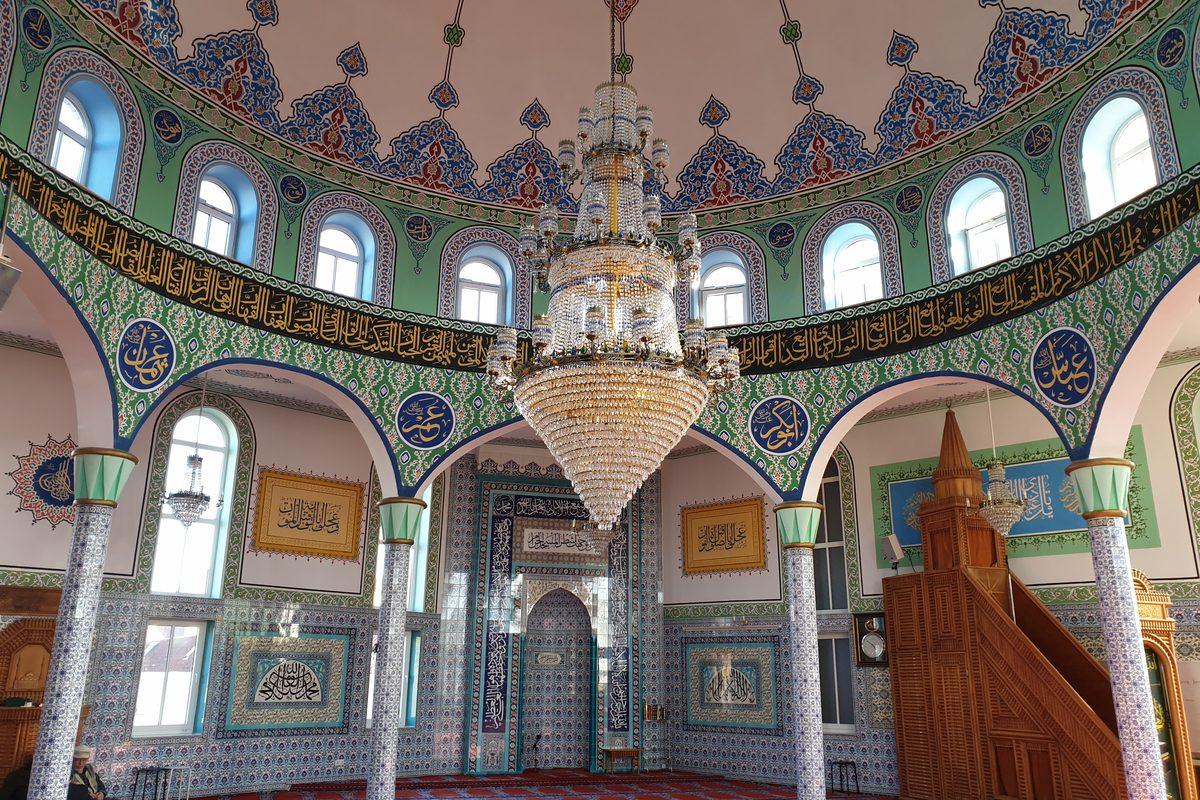 Gebetsraum einer Moschee mit Kronleuchter, Kuppel und Minbar