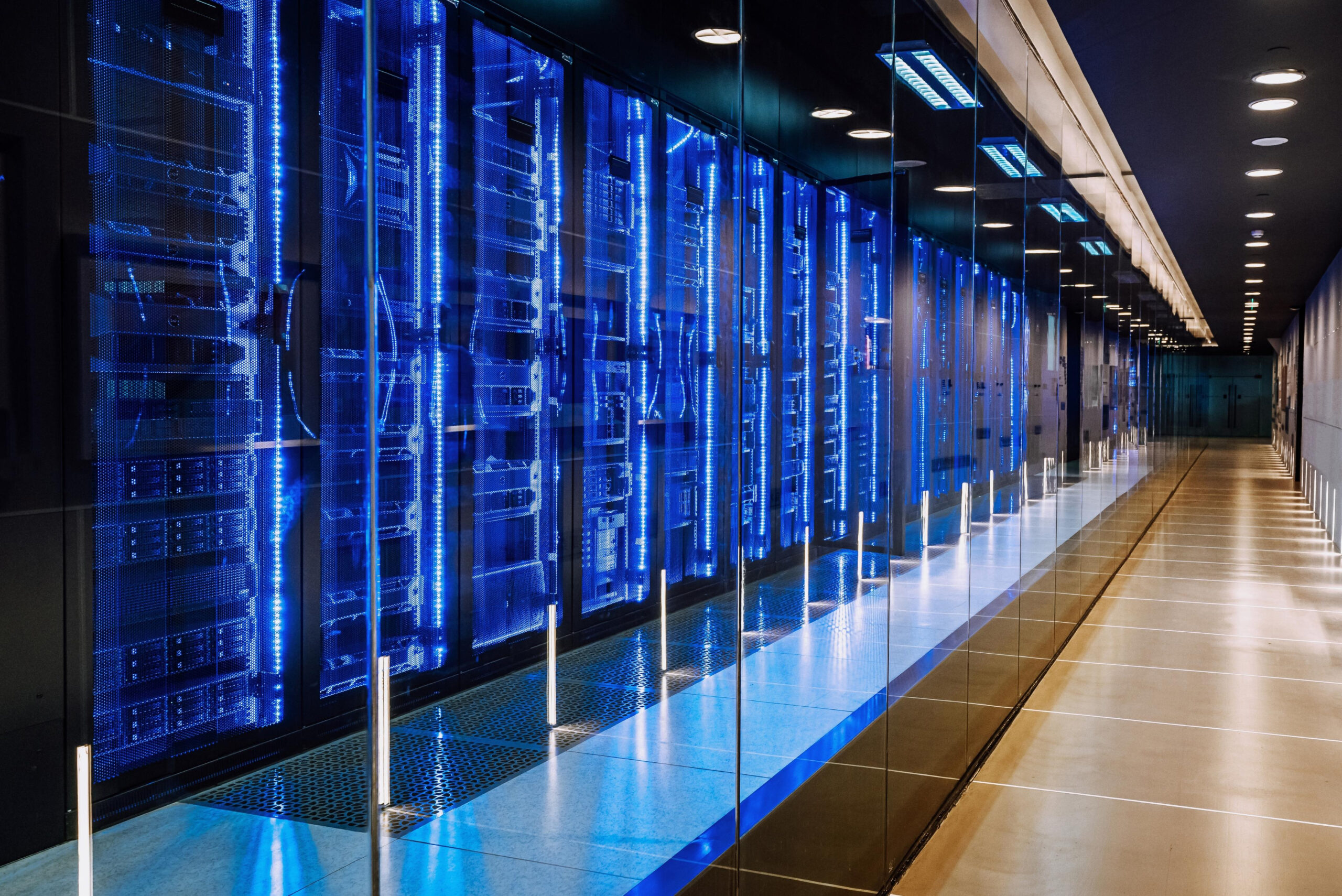 Blick in ein modernes Rechenzentrum mit blau beleuchteten Serverracks hinter Glas.